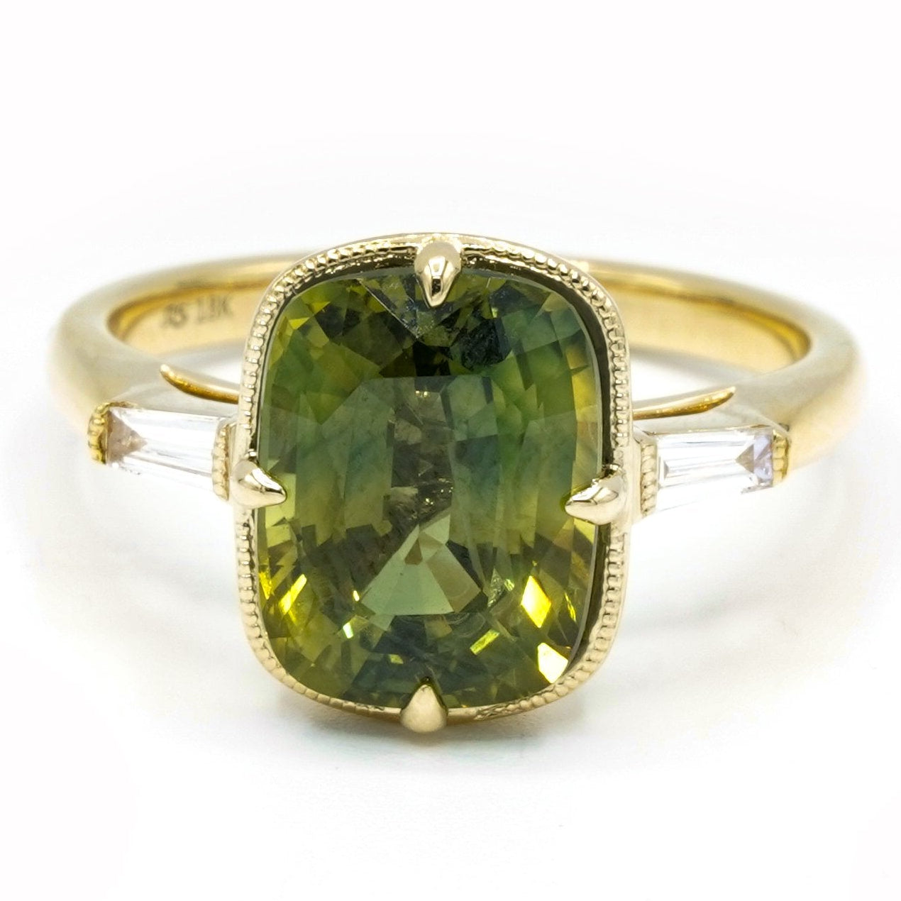 Gold ring with a green sapphire gemstone on a white background