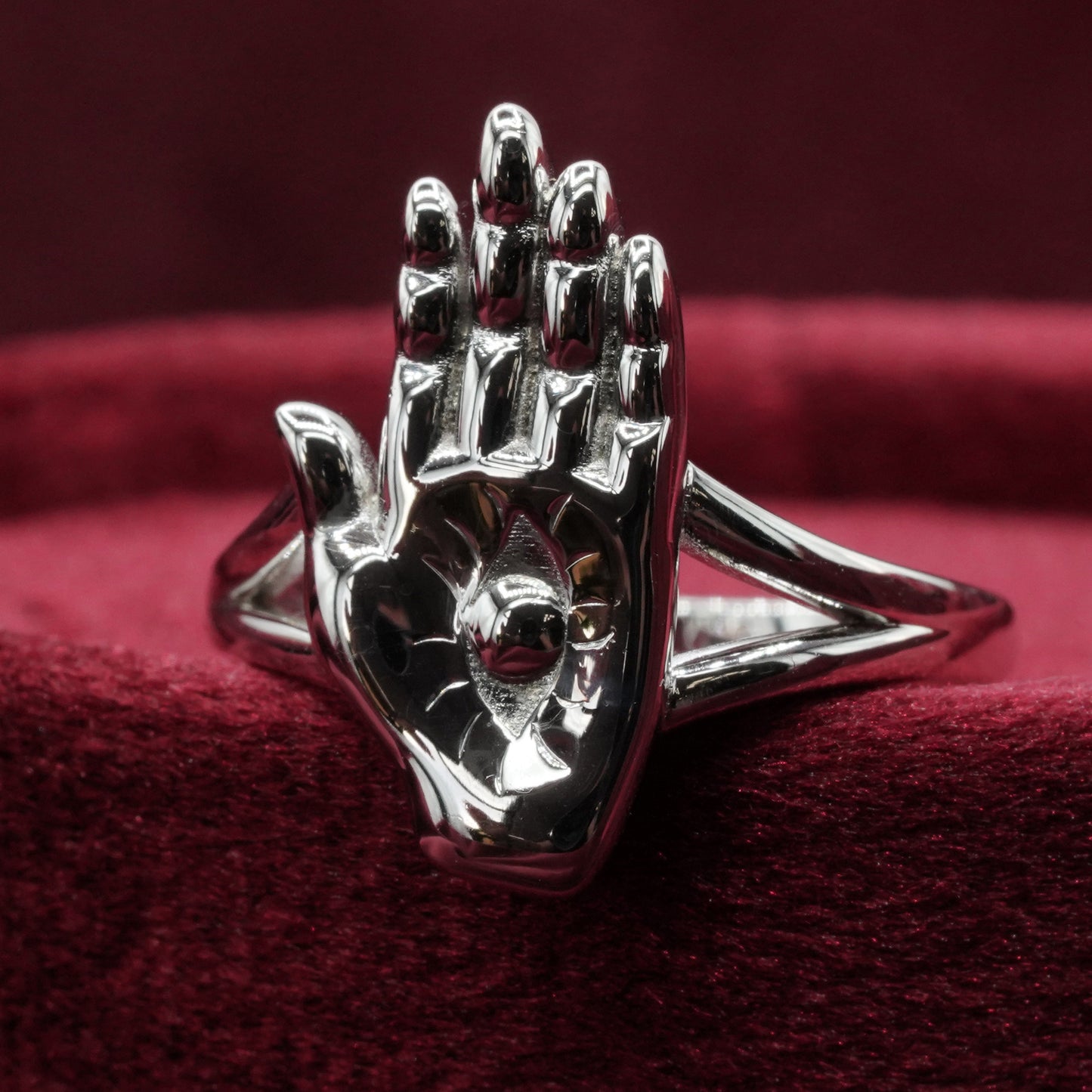 Silver hand-shaped ring on a red fabric background