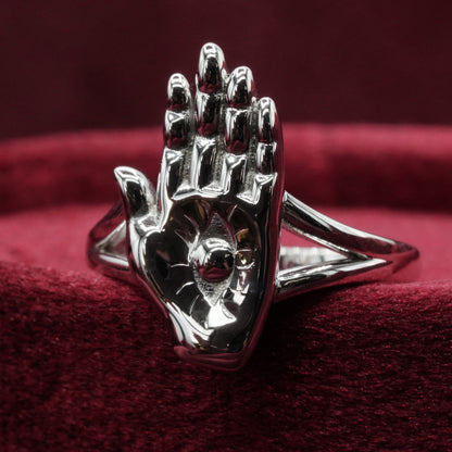 Silver hand-shaped ring on a red fabric background