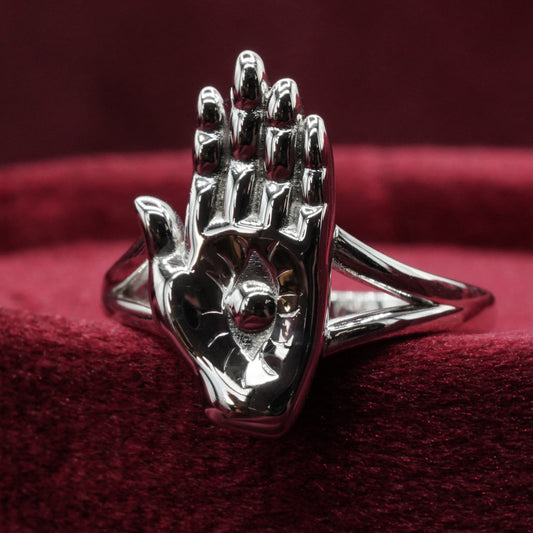 Silver hand-shaped ring on a red fabric background